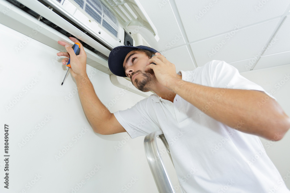 young handyman repairing air conditioning system calling for help young handyman repairing air conditioning system calling for help