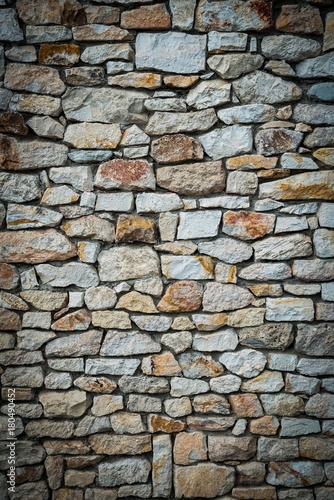 Stone wall background of colorful stones. Vignetted borders. Vertical photo