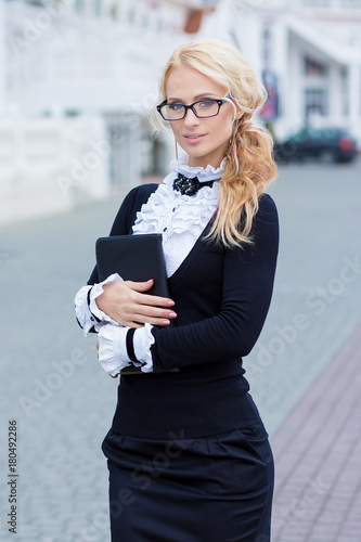 Business lady woman dressed in working serious skirt and shirt posing on street with note book blond hairs and pink high heels sexy
