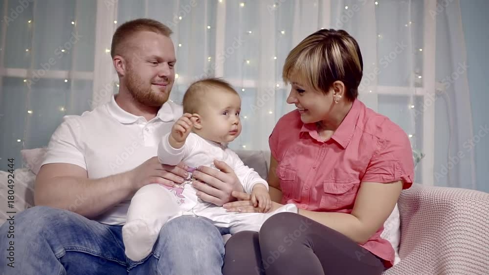 young mother with short hair trying to entertain and attract the attention of his little daughter who sits at the feet of the male parent young mother with short hair trying to entertain and attract the attention of his little daughter who sits at the feet of the male parent