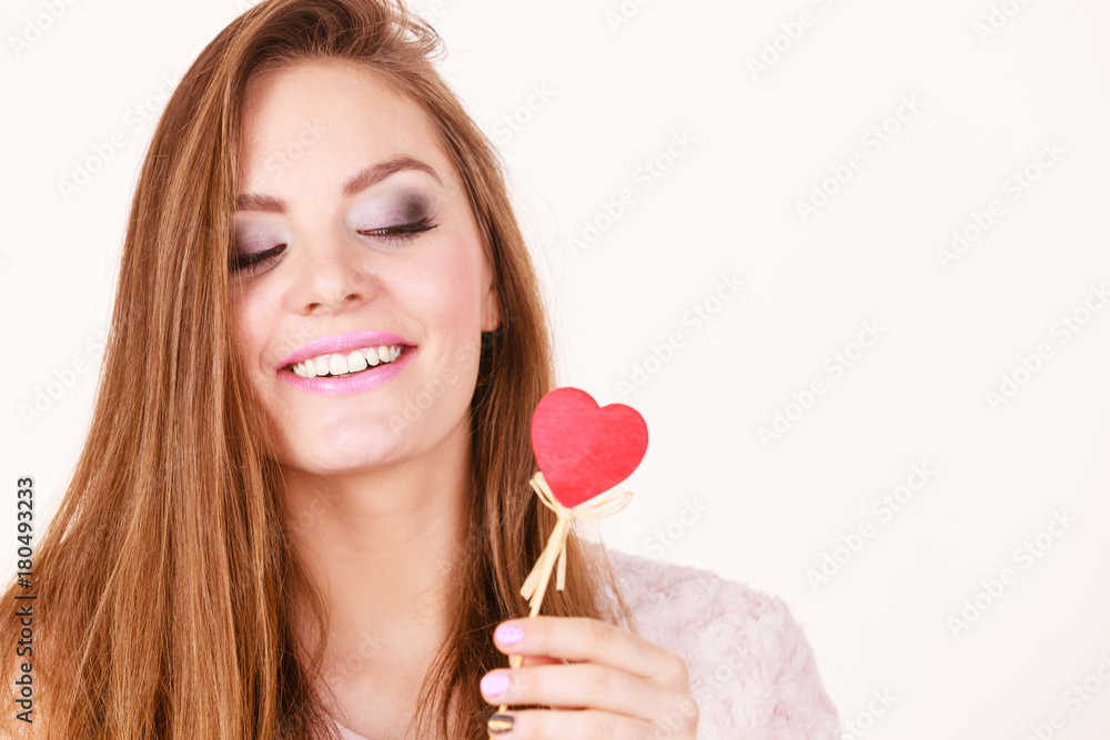 Flirty woman holding red wooden heart on stick Flirty woman holding red wooden heart on stick