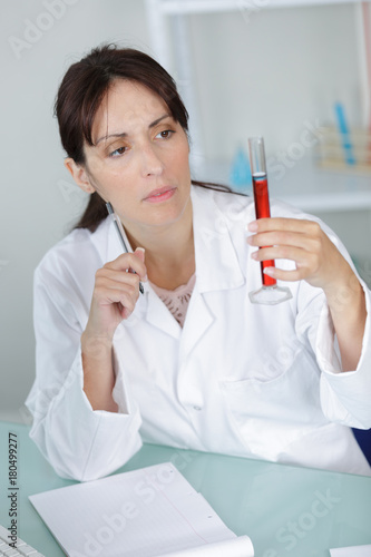 middle-age female doctor writing on a blood sample