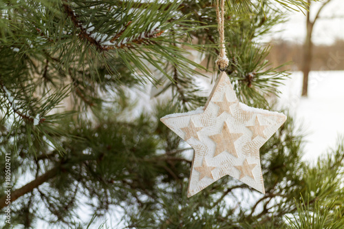 Christmas decor wooden star on the green fir branch in snowflakes photo