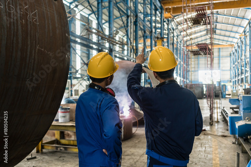Принти на полотні Two Asian experts talking while supervising the fabrication of industrial boiler