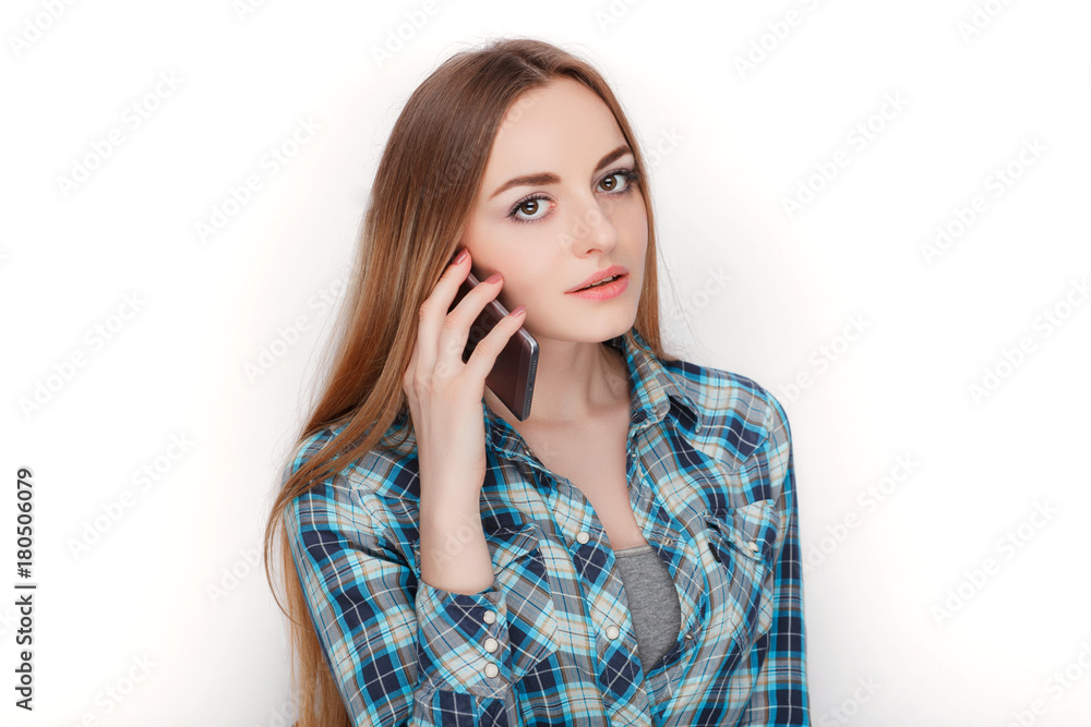 Portrait of a young adorable blonde woman in blue plaid shirt enjoying having emotional conversation on smartphone. Portrait of a young adorable blonde woman in blue plaid shirt enjoying having emotional conversation on smartphone.