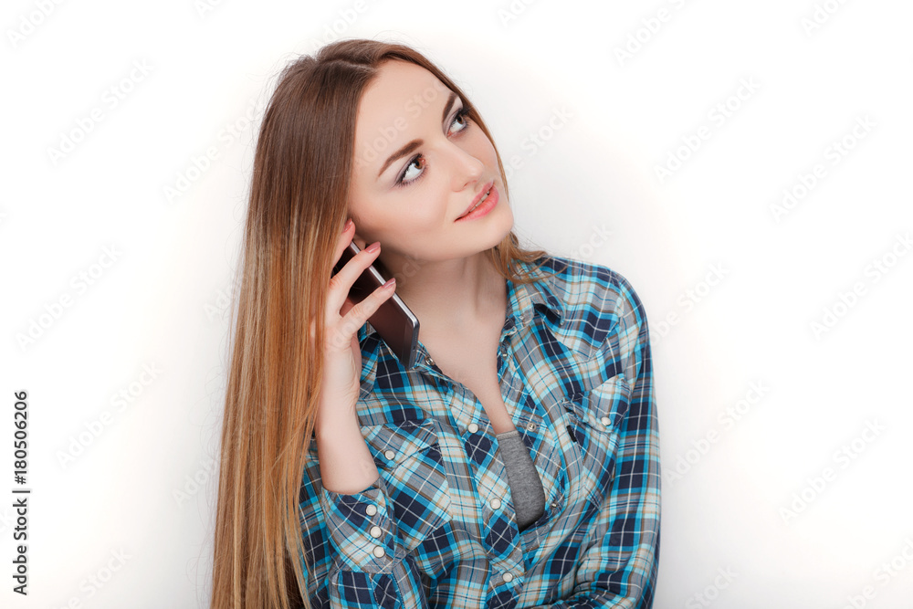Portrait of a young adorable blonde woman in blue plaid shirt enjoying having emotional conversation on smartphone. Portrait of a young adorable blonde woman in blue plaid shirt enjoying having emotional conversation on smartphone.