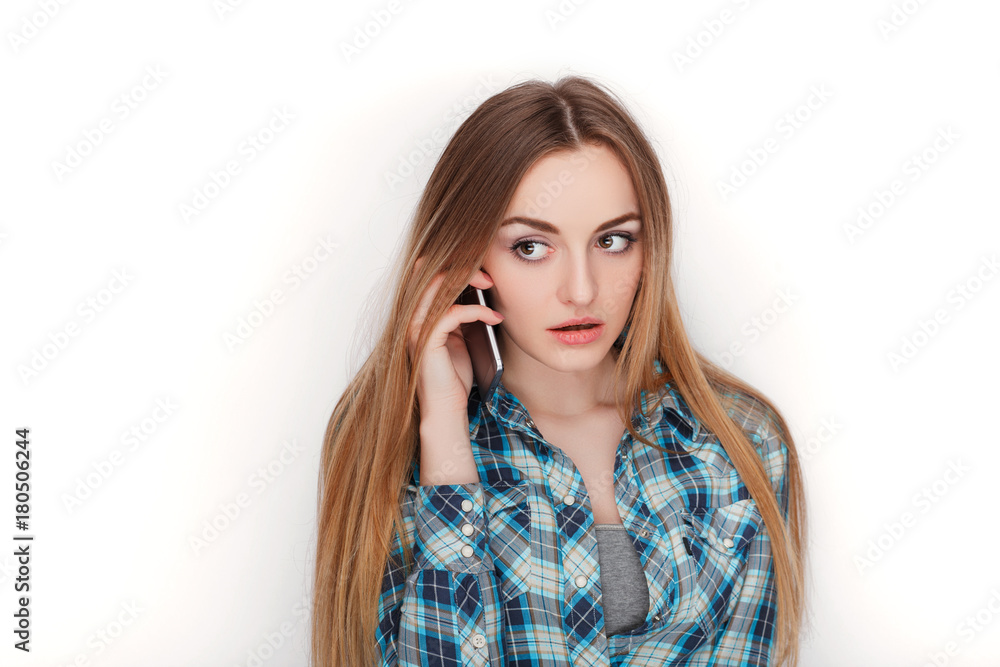 Portrait of a young adorable blonde woman in blue plaid shirt enjoying having emotional conversation on smartphone. Portrait of a young adorable blonde woman in blue plaid shirt enjoying having emotional conversation on smartphone.