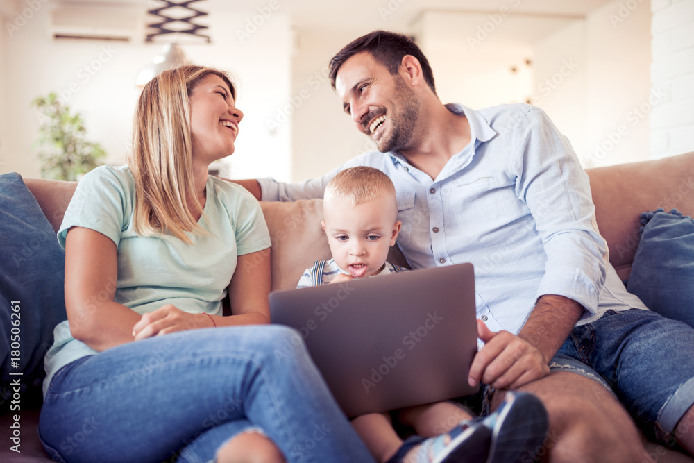 Happy family using laptop together on sofa in house. Happy family using laptop together on sofa in house.