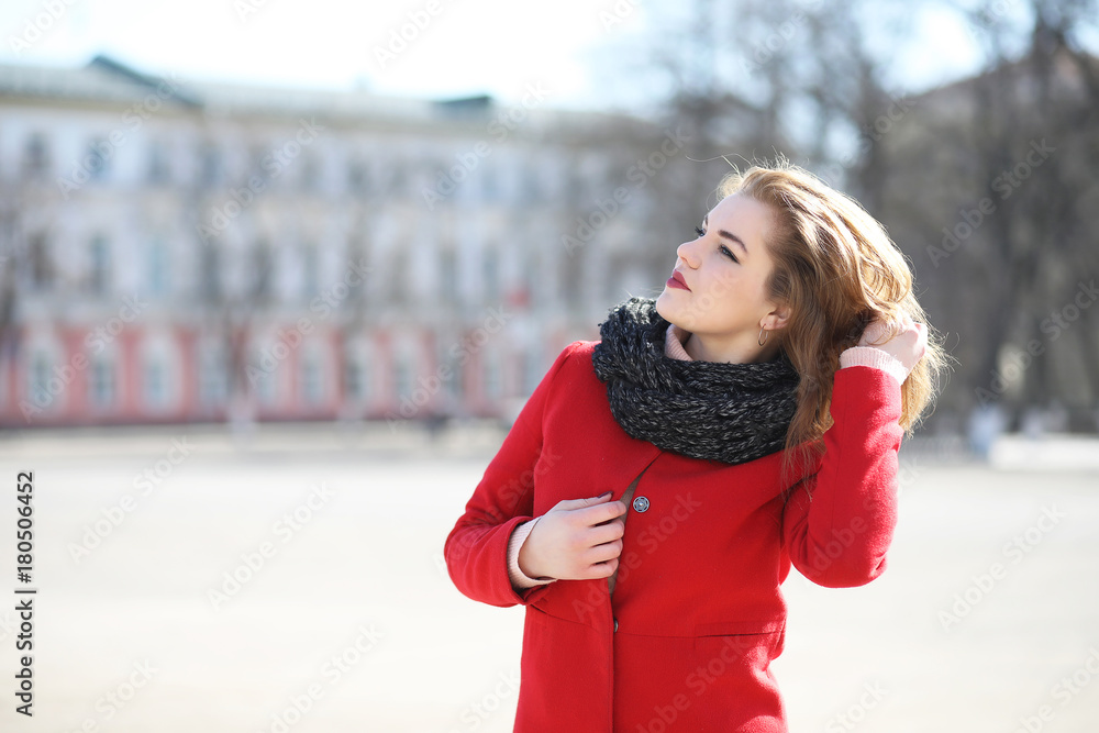 Fototapeta premium Pretty girl on a walk in red coat in the city
