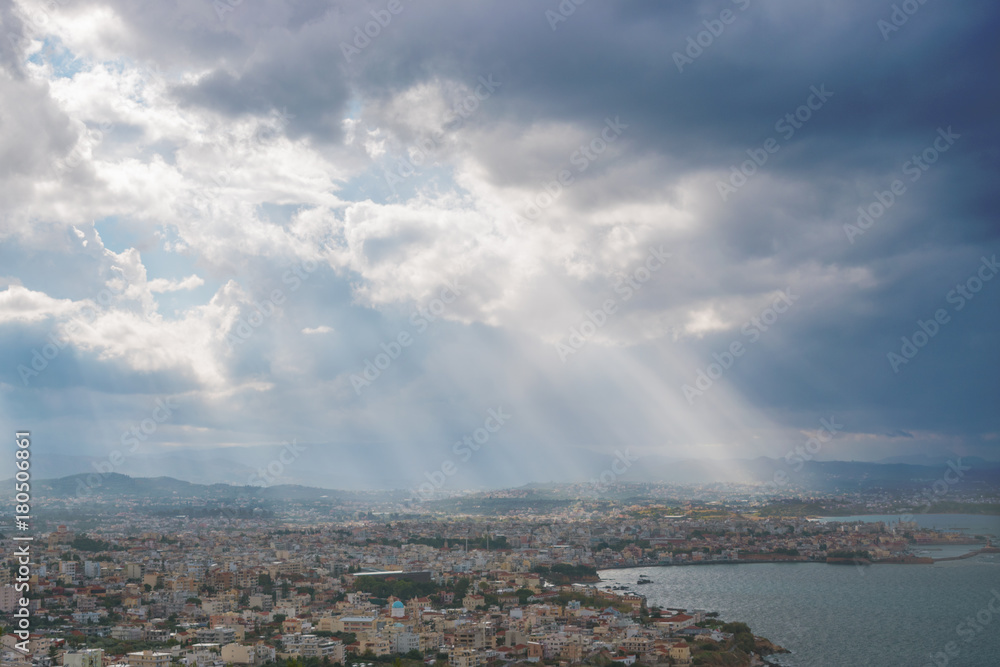 Sunbeams shining through the dramatic clouds over the city Chania. Greece. Crete.