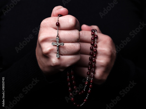 Photography Female hands praying holding a rosary with Jesus Christ in the cross or Crucifix on black background