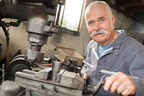 happy senior worker operates metalworking machine