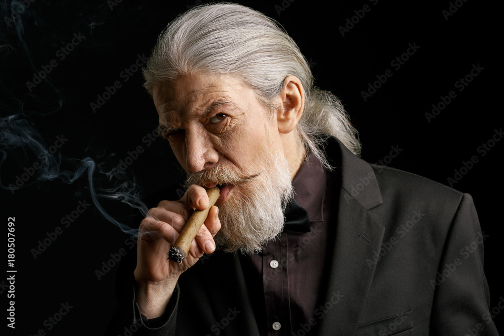Stylish aged man with long grey hair smoking cigar. Portrait of wrinkled  male with cigar on black background. Stock Photo | Adobe Stock