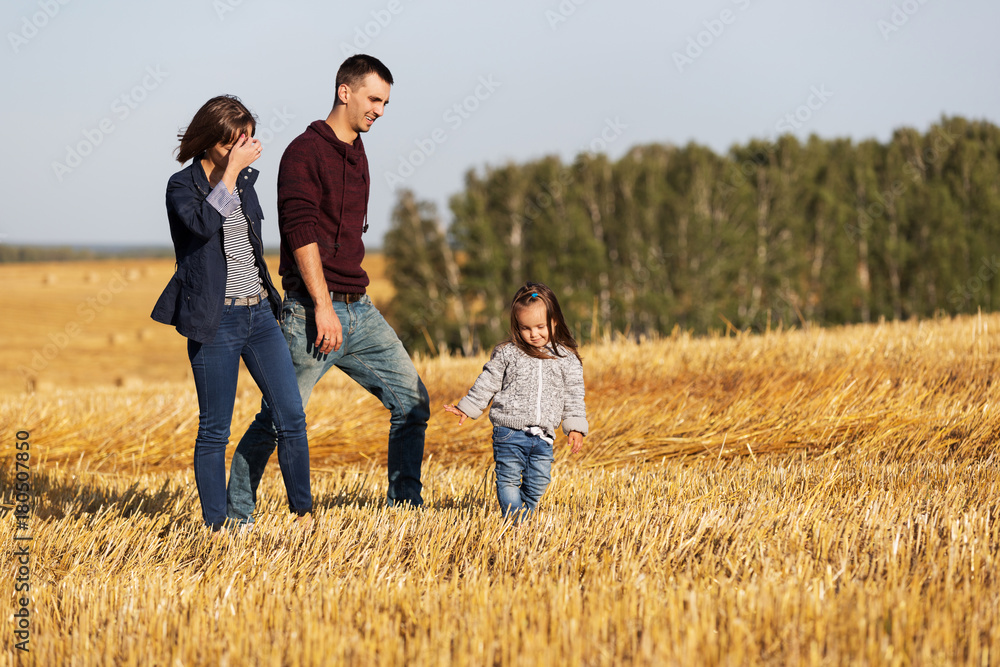Happy young family with two year old girl walking in a harvested field Happy young family with two year old girl walking in a harvested field
