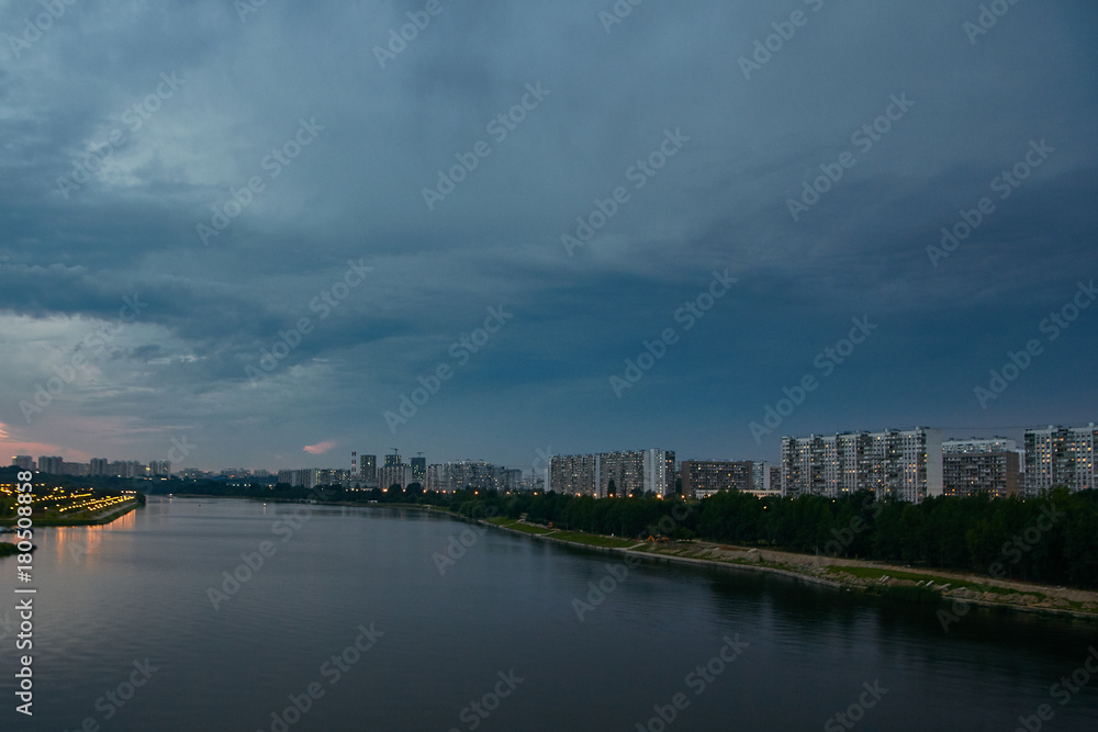 Cityscape at dusk with thunderstorm over apartments buildings