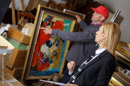 man holding and showing a painting to auctioneer before auction