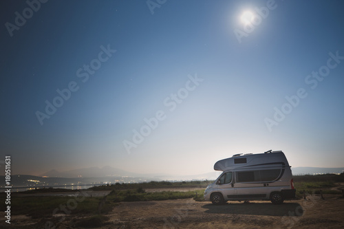 Motorhome RV and campervan are parked on a beach. Motor home caravan are parked on a parking space for RV van vehicles by Aegean sea in Greece. Night scenery.