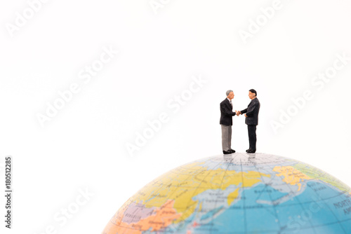 business miniature people handshaking on the globe isolated on white background