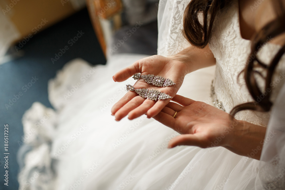 Bride in white wedding dress holding bridal jewelry. Wedding concept