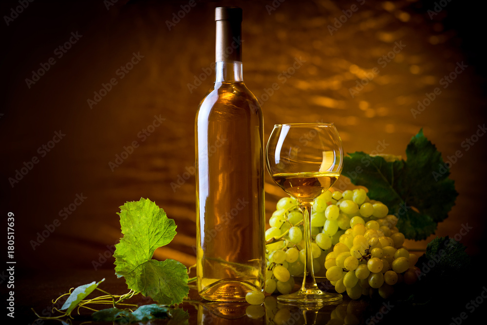 Fototapeta premium Wine. Bottle and a glass of white wine with ripe grapes still life. White wine on a gold background. Christmas wine
