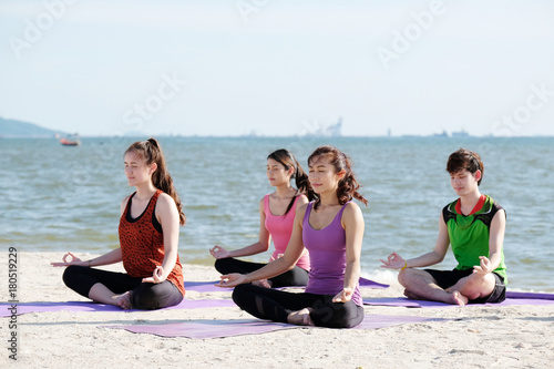 Group of young healthy asian people practicing yoga on the beach, healthy lifestyles, wellness, well being
