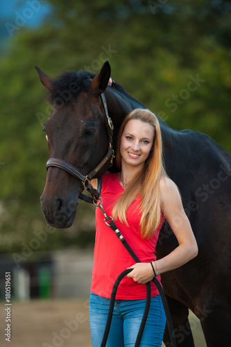 Beautiful young woman with horse outdoor on a walk in nature