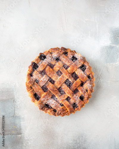 American cherry pie, powdered sugar on a gray concrete background. Copy Space. View blank space for text. Place for text. Food photo. Flat lay, top view Piece of cake in a wooden box. Craft Newspaper