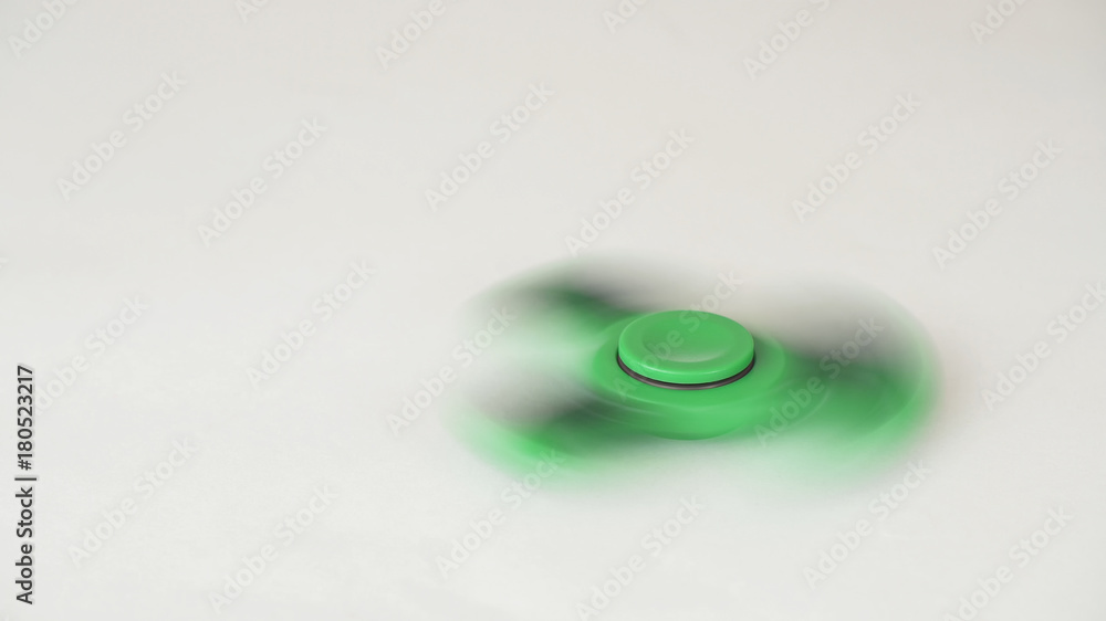 Green fidget spinner turns and stops on white background Green fidget spinner turns and stops on white background