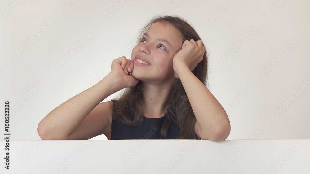 Beautiful girl teenager joyfully dreams over the poster with information on white background Beautiful girl teenager joyfully dreams over the poster with information on white background