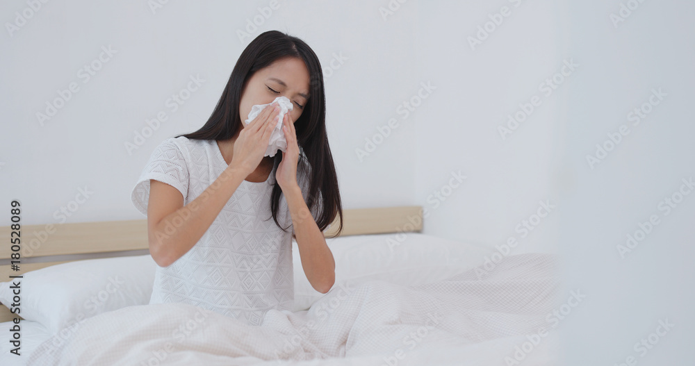 Woman sneezing on bed Woman sneezing on bed