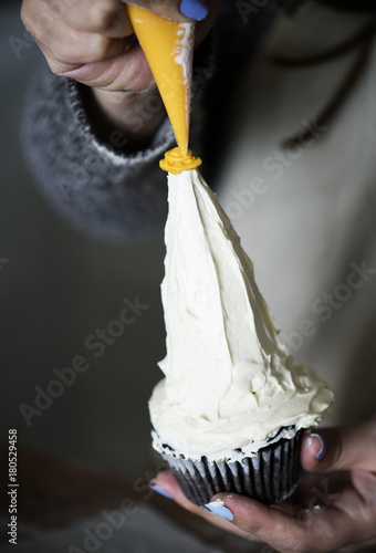Baker decorating a cupcake