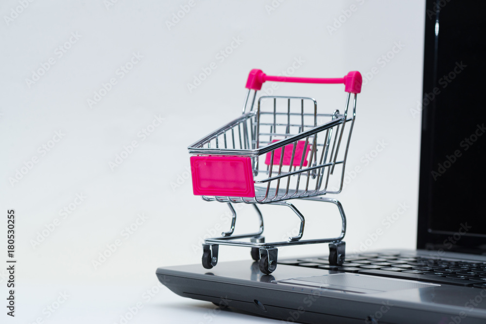 Shopping cart or supermarket trolley with laptop notebook on white background, e-commerce and online shopping concept.