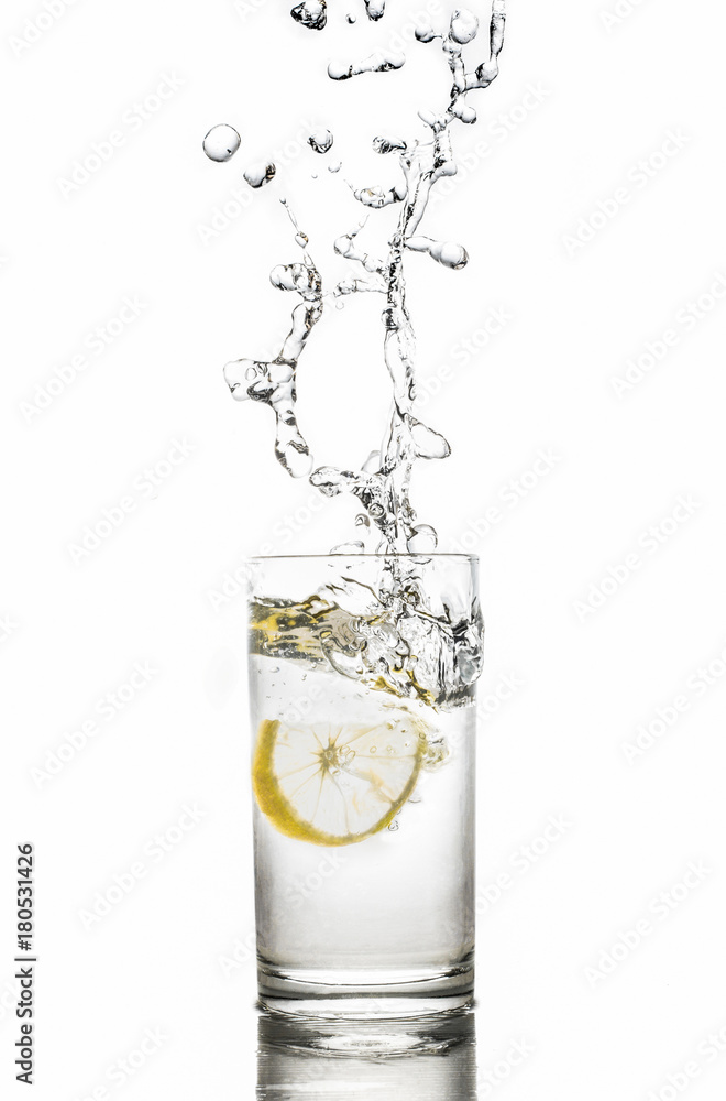 Lemon splashes in water glass isolated on white background Lemon splashes in water glass isolated on white background