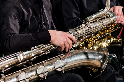 A saxophonist man put a baritone saxophone on his knees and waits for the orchestra's performances. photo