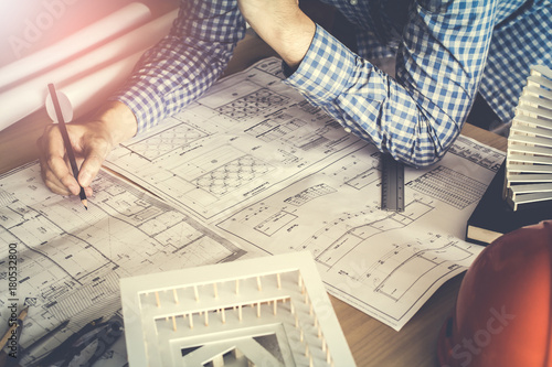 Concept architects,engineer holding pen pointing equipment architects On the desk with a blueprint in the office, Vintage, Sunset light.Selective Focus