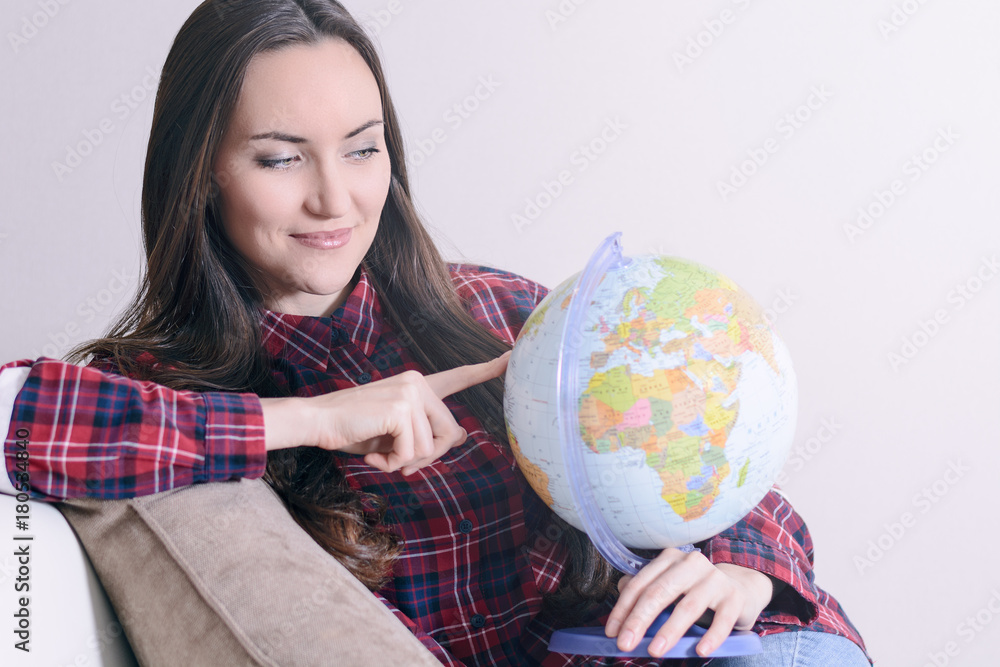 Go on an adventure. Woman dreaming about traveling around the world, looking at the globe in room of the house. Pretty girl study the globe and choose a route of travel Go on an adventure. Woman dreaming about traveling around the world, looking at the globe in room of the house. Pretty girl study the globe and choose a route of travel