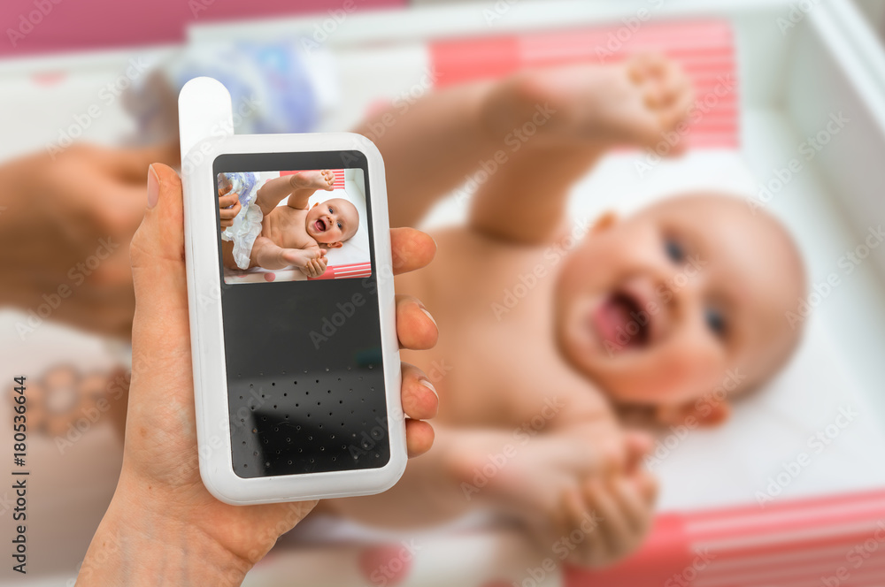 Mother is holding baby monitor camera for safety of her baby