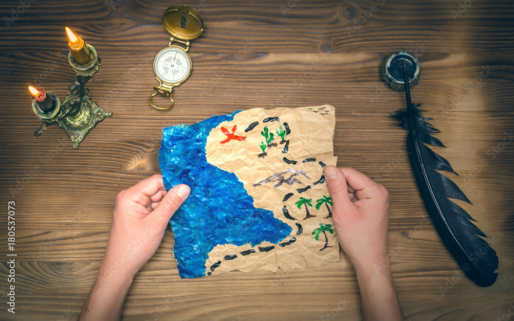 Treasure map and compass on wooden table. Treasure hunt background.  Adventurer man holding in hands a treasure map and learning it. Stock Photo  | Adobe Stock