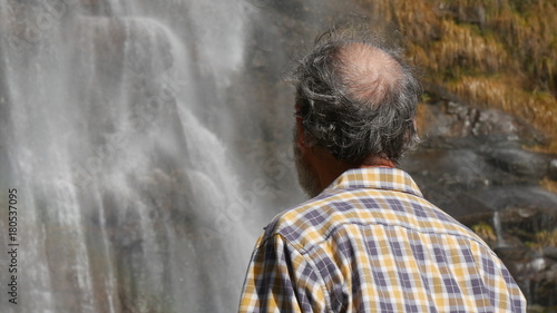 Uomo pensieroso e solitario osserva una cascata selvaggia