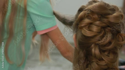 A professional stylist makes a hairstyle for the model. Fashion world.