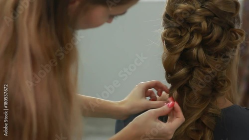 A professional stylist makes a hairstyle for the model. Fashion world.