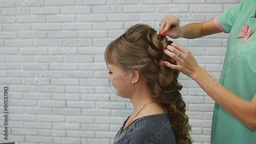 A professional stylist makes a hairstyle for the model. Fashion world.