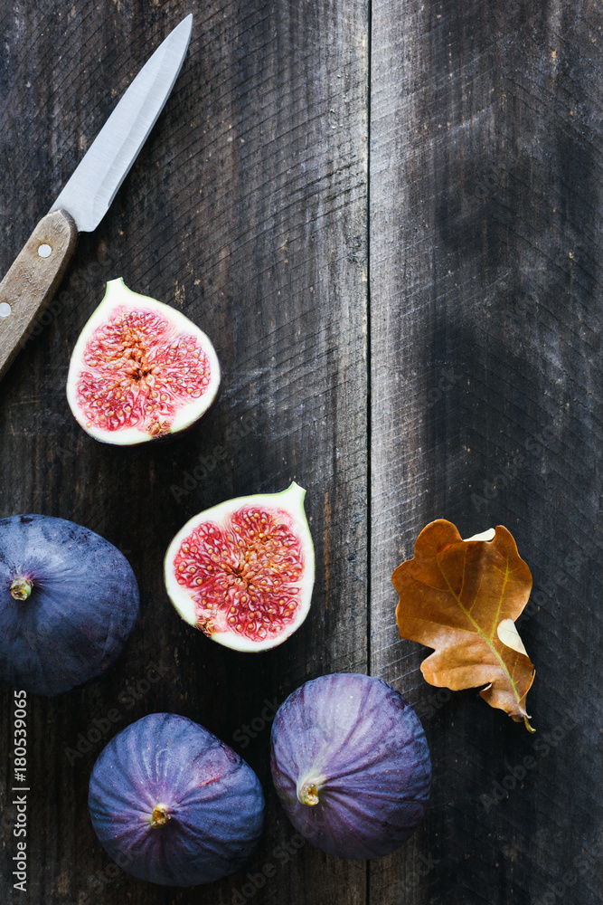 Fresh purple figs and table knife on old wooden background with copy space for text. Top view