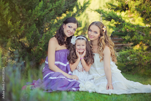Stunning Brunette blond chestnut blue eyes sisters girls wearing stylish white purple dress enjoying life time together summer sunny day in garden forest on green grass happy smiling photo