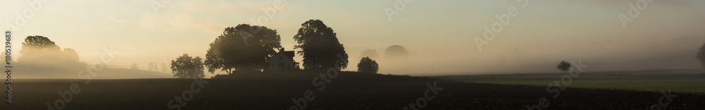 A very special panorama picture, mystic and eventful with trees and fog hanging over a farm building in the center of the panorama. A very special panorama picture, mystic and eventful with trees and fog hanging over a farm building in the center of the panorama.