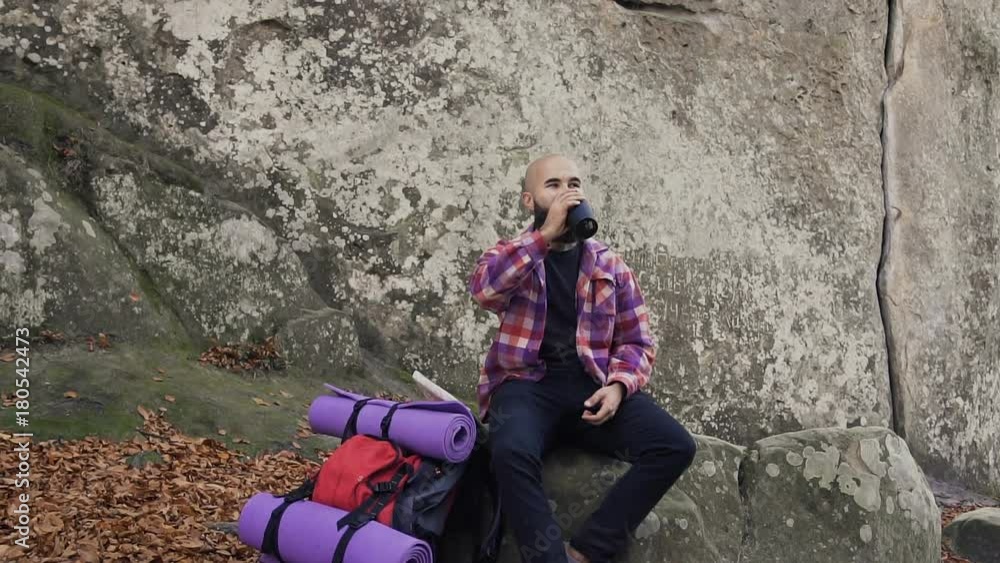 The tourist went to rest on a rock ,near a high cliff took out a warm cup of tea from the backpack, drink tea and enjoy the warm autumn weather The tourist went to rest on a rock ,near a high cliff took out a warm cup of tea from the backpack, drink tea and enjoy the warm autumn weather