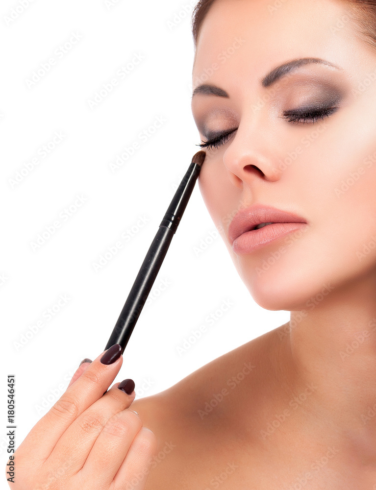 Pretty woman holds two makeup brushes, isolated on white background