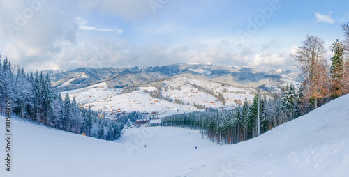 Ski slope against of mountain range and village in Carpathians