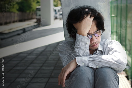 Frustrated stressed young Asian man touching head and feeling disappointed or exhausted. Unemployed businessman concept.