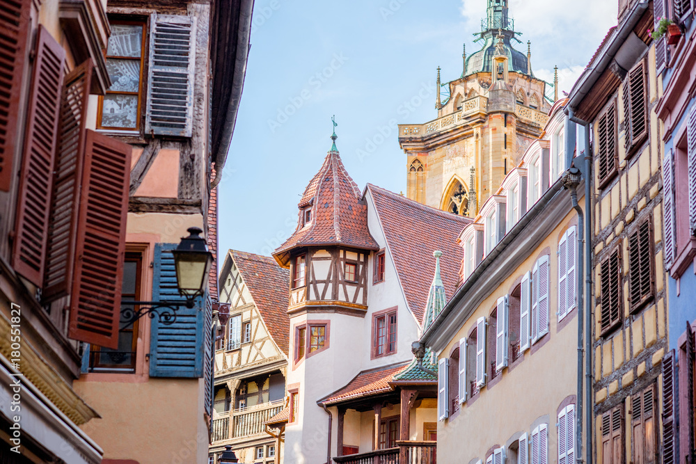 Obraz premium Street view on the beautiful old buildings with cathedral tower in the famous tourist town Colmar in Alsace region, France